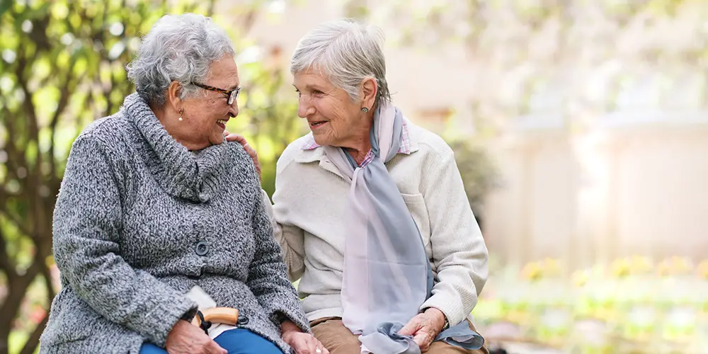 Outdoor, friends and bench with senior women, love and bonding together with retirement, park and cheerful. Old ladies, outside and mature people with conversation, group and joy with weekend break